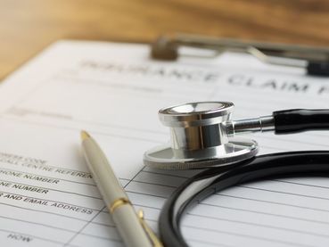 insurance claim document with a pen and stethoscope