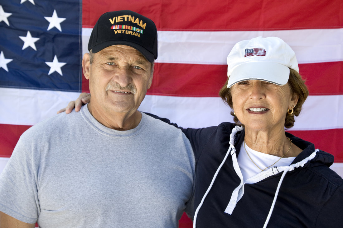 Vietnam veteran and his wife in front of an American flag
